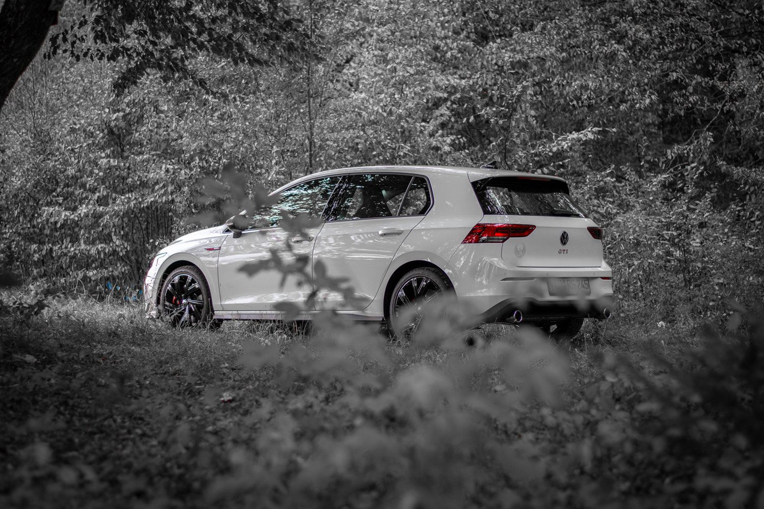 White VW Golf GTI in a forest, selective colour edit
